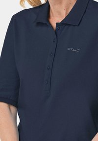 Marineblaues Poloshirt mit Kragen, kurzen Ärmeln und Knopfleiste. Besitzt ein dezentes gesticktes Design auf der Brust. Aus strukturiertem Stoff gefertigt.