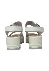 I sandali platform bianchi presentano una parte superiore in sintetico liscio con doppi cinturini, un tacco basso e una suola testurizzata per una buona aderenza. Completati da una piccola fibbia.