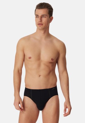 Svarta bomullsbriefs med en slät yta, utrustade med en bekväm midjeresår och kontrasterande sömnad.