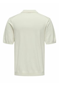 Polo a maniche corte color avorio, con colletto piatto, polsini a costine e una morbida trama a maglia caratterizzata da un design semplice e pulito.