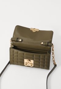 Borsa a tracolla in pelle trapuntata verde oliva con chiusura in tonalità oro, tracolla a catena e diversi scomparti interni.