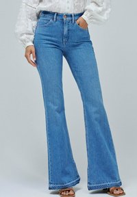Jeans acampanados de talle alto en denim azul claro, con un diseño de cinco bolsillos y detalles de dobladillo sin terminar. Textura suave con un ligero estiramiento.