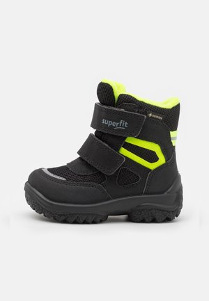 Botte d’hiver enfant noire et jaune fluo avec une semelle texturée, deux bandes velcro et un marquage Gore-Tex pour une protection imperméable.
