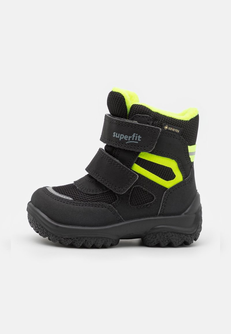 Botte d’hiver enfant noire et jaune fluo avec une semelle texturée, deux bandes velcro et un marquage Gore-Tex pour une protection imperméable.