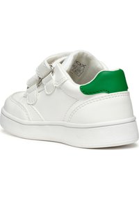 Baskets synthétiques blanches avec un accent vert au talon, dotées de deux bandes Velcro et d'une semelle en caoutchouc blanc texturé.
