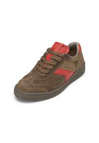 Sneaker in suede marrone con accenti rossi, caratterizzato da un design con lacci, suola in gomma testurizzata e logo impresso sulla linguetta.