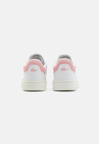 Une paire de baskets blanches avec des panneaux de talon en maille rose et des logos crocodile roses, vue de l'arrière sur un fond blanc uni.