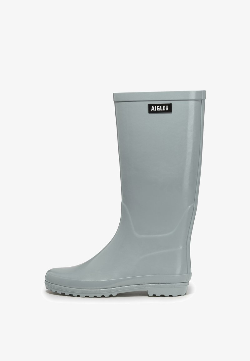 Botte de pluie haute en caoutchouc gris clair avec semelle texturée et étiquette de marque Aigle près du haut sur fond blanc uni.