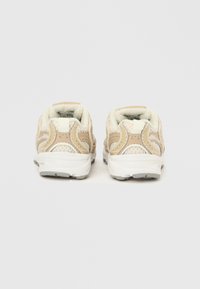 Μπεζ αθλητικά παπούτσια με διχτυωτό και συνθετικό επάνω μέρος, επένδυση στο κολάρο, και λευκή καουτσούκ σόλα. Διαθέτουν καμπυλωτές λεπτομέρειες και θηλιά στο πίσω μέρος.