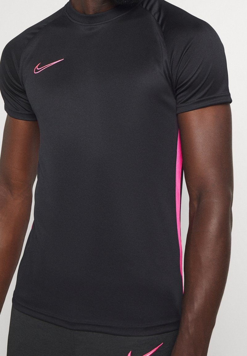 Sort trænings T-shirt med korte ærmer, der har pink accenter og et lille logo nær halsudskæringen. Glat, tætsiddende design.