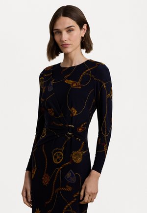 Robe à manches longues en tissu bleu marine, ornée d'un motif en chaîne dorée et d'emblèmes, cintrée à la taille avec un détail de boucle ronde dorée.