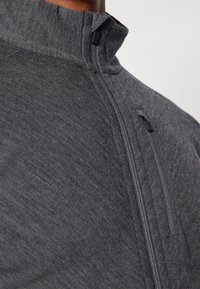 Tmavě šedá zipová bunda s vysokým límcem, strukturovanou tkaninou a bočním zipovým kapsou. Minimalistický design bez viditelných log a vzorů.