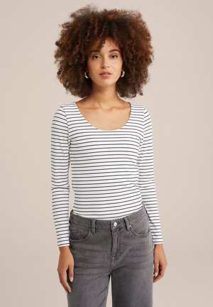 Gestreiftes Langarmoberteil in Weiß und Schwarz mit U-Boot-Ausschnitt und geripptem Textur, kombiniert mit grauen hoch taillierten Jeans.