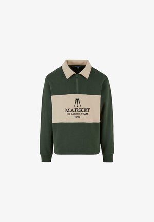 Zielona i beżowa longsleeve polo bluza z zamkiem przy kołnierzu, z napisem "MARKET US RACING TEAM 1993" nadrukowanym na środku na czarno.