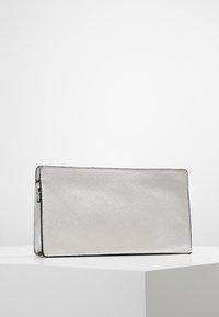 Pochette metallica argento con superficie liscia, forma rettangolare e design minimalista. Dotata di chiusura a zip e bordi neri.