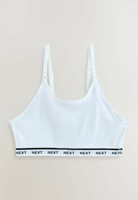 Bijela pamučna bralette s podešivim naramenicama i elastičnom trakom koja ima crni logotip "NEXT" koji se ponavlja oko donjeg ruba.