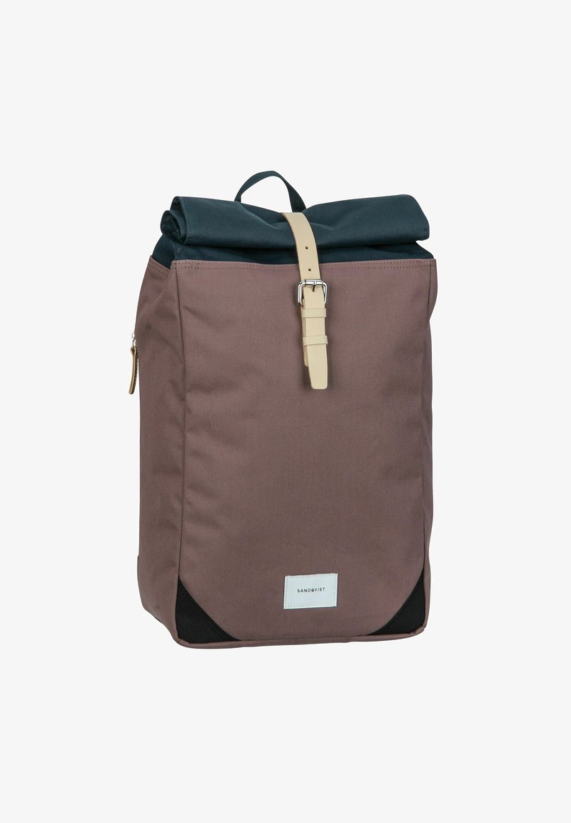 Rolled-top backpack in dark blue and brown canvas. Features a leather strap with a metal buckle, side zip pocket, and black accents.