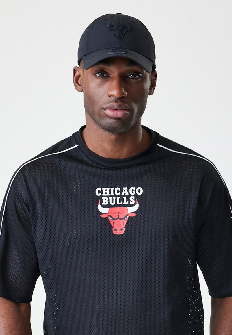 Svart mesh sportsjersey med en rød og hvit "Chicago Bulls" logo på brystet. Kombinert med en matchende svart caps.