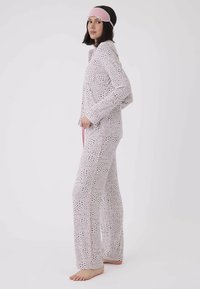 Ljust rosa leopardmönstrad pyjamasett med långa ärmar, matchande byxor och kontrasterande rosa kant. Inkluderar en rosa ögonmask. Mjuk tyg.
