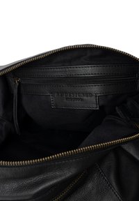 Schwarzes Lederhandtascheninnere mit einem Reißverschlussfach; texturierte Stoffauskleidung und ein Reißverschluss in Goldton weisen auf sichere Aufbewahrungsmöglichkeiten hin.