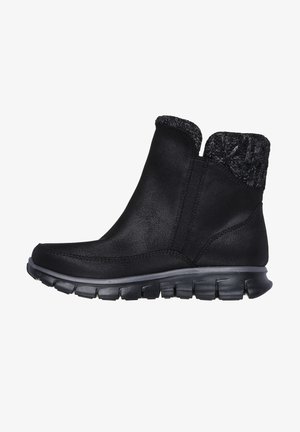 Bottines noires en matériau synthétique avec un col en tricot texturé, un bout courbé et une semelle en caoutchouc épaisse et segmentée.