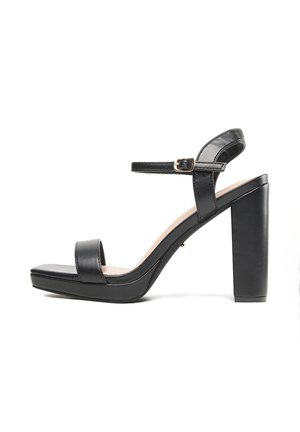 Sandales à plateforme en cuir noir avec une large bride sur le pied, une bride de cheville avec boucle, et un talon carré épais. Texture lisse.