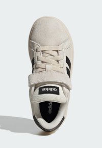 Beige suède sneaker met zwarte strepen en klittenbandsluiting. Lichte mesh voering en zwarte binnenzool met logo. Ronde neus en gevoerde zool.