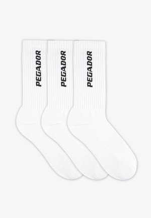 White cotton socks in a pack of three, featuring ribbed texture and printed "PEGADOR" in black on each sock. No graphic elements.