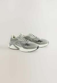 Baskets de sport grises avec dessus en mesh et synthétique, épaisse semelle intermédiaire blanche et accents texturés. Bout arrondi et design à lacets.