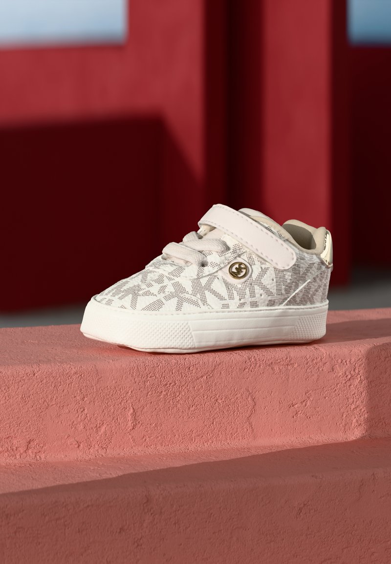 Light pink toddler shoe made of patterned textile with a white rubber sole. Features a Velcro strap and a logo accent on the side.