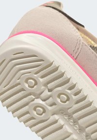 Svetlosivá tenisová topánka s ružovým akcentom pri päte; textúrovaná gumová podrážka so vzorom dezénu; značenie na boku.