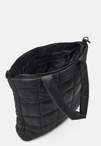 Czarna pikowana torba tote z wyściełanymi uchwytami, z otwartym zamek u góry i widoczną wewnętrzną kieszenią na zamek.