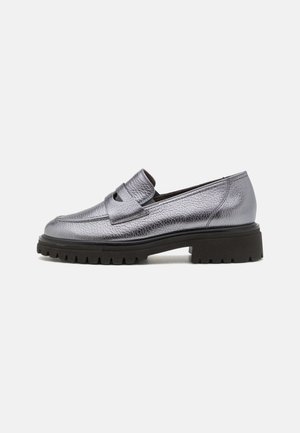 Metallic sølv læder loafers med tykk sort lug-sål og penny strap detalje, vist fra siden på en hvid baggrund.