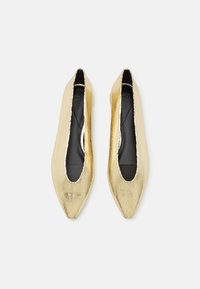 Bailarinas doradas con una textura agrietada, diseño de punta afilada y un corte profundo en los laterales, con un forro interior negro.