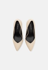 Paire de chaussures plates beiges à bouts pointus avec semelles intérieures noires, de marque "Even & Odd,", vues de dessus sur fond blanc.