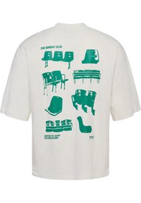 White t-shirt featuring a green graphic print of various chair designs on the back, labeled "THE SUNDAY CLUB" and "SERVING THE GAME FOR GENERATIONS."