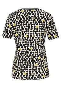 T-shirt à manches courtes avec une texture côtelée, un fond crème et un motif éparpillé de formes noires, vertes et jaunes.