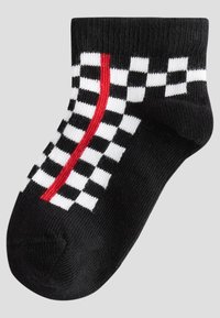 Calzino nero alla caviglia con motivo a scacchi bianco, caratterizzato da una striscia verticale rossa. Realizzato in un morbido materiale a maglia testurizzata.