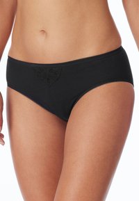 Zwarte katoenen slip met een decoratief reliëfontwerp aan de voorkant en contrasterende golvende randen langs de tailleband en beenopeningen.
