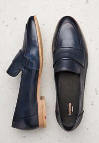 Mocasines de cuero azul marino con punta redondeada, una tira ancha en la parte superior y un bajo tacón de madera. Plantilla texturizada con marca.