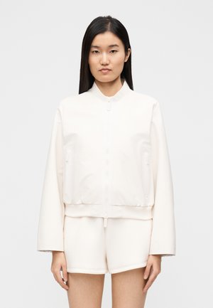 Leichte cremefarbene Bomberjacke mit Reißverschluss vorne, geripptem Saum und zwei Seitentaschen. Verfügt über ein schlichtes Design und eine glatte Textur.