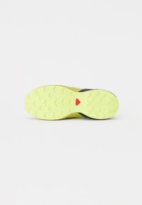 Sorte av løpesko til terrengtrening i svart og neongul med en teksturert gummisåle og et rødt aksent i sentrum. Flat og bred design.