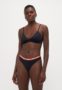 Zwarte bikini met een driehoekige bralette met dunne bandjes en een korte onderkant. De tailleband heeft een contrasterende roze logo-accent.