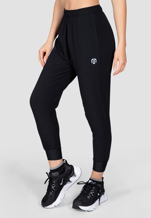 Sorte sporty joggers med elastisk talje, afsluttede ankler og hvide sideaccenter. Har et lille logo på venstre hofte.