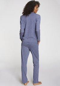 Plava pidžama koja se sastoji od dugih rukava i ravnih hlača, s vertikalnim prugastim uzorcima u svijetlo ružičastoj boji. Izrađena od glatkog, laganog materijala.