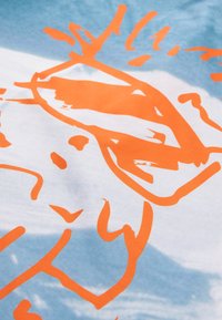 Bomuldsstof med en blå baggrund og et abstrakt orange design, der fremhæver kraftige linjer og former. Blød tekstur, glat finish.