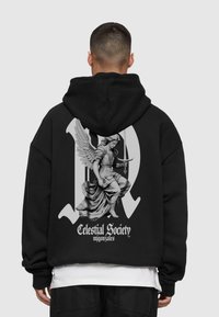 Schwarzer Hoodie mit einem großen grauen Grafik eines Engels, der ein Schwert hält, überlagert auf einem stilisierten "R", mit dem Text "Celestial Society" darunter.