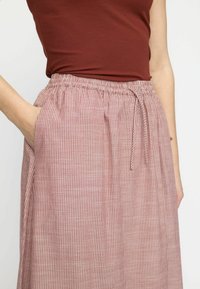 Rosa och vit randig kjol med elastisk midja, snörning och sidofickor. Tillverkad av lätt tyg med avslappnad passform.