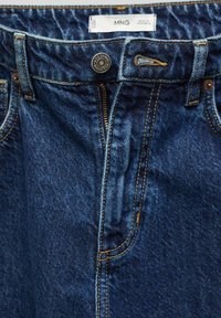 Modré džíny z denimu se zapínáním na zip, kovovým knoflíkem a kontrastním oranžovým prošíváním. Obsahují pas s poutky na opasek a postranní kapsy.