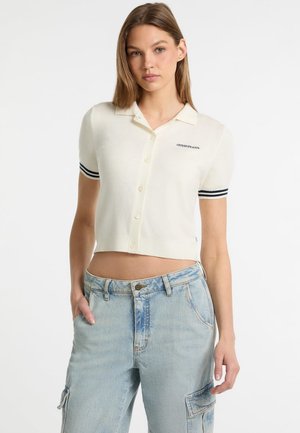Korte mouwen crème poloshirt, met marineblauwe strepen op de manchetten en knoopsluiting, geborduurd logo op de linkerborst.